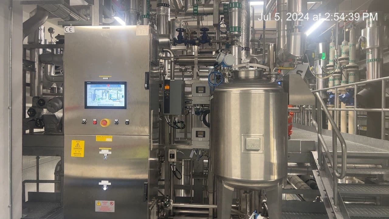 Stainless-steel process skid with a control panel, vessel, valves, and hygienic piping.