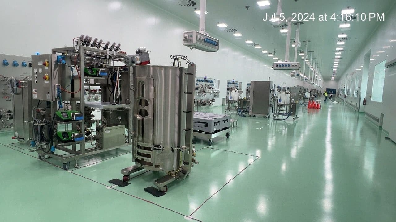 Stainless-steel process equipment arranged along a cleanroom corridor with ceiling services.