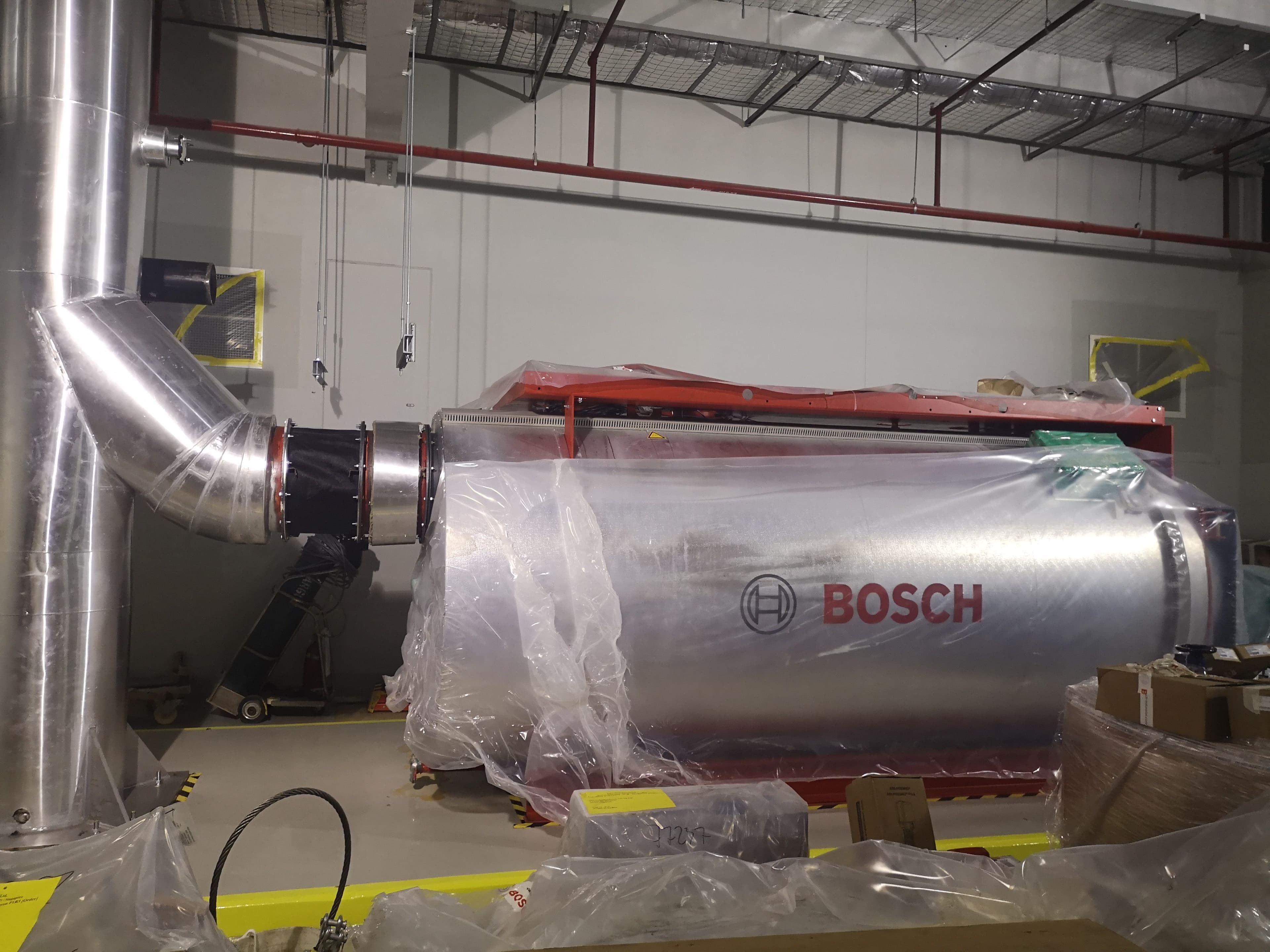 Packaged hot-water boiler connected to insulated exhaust ductwork during installation.