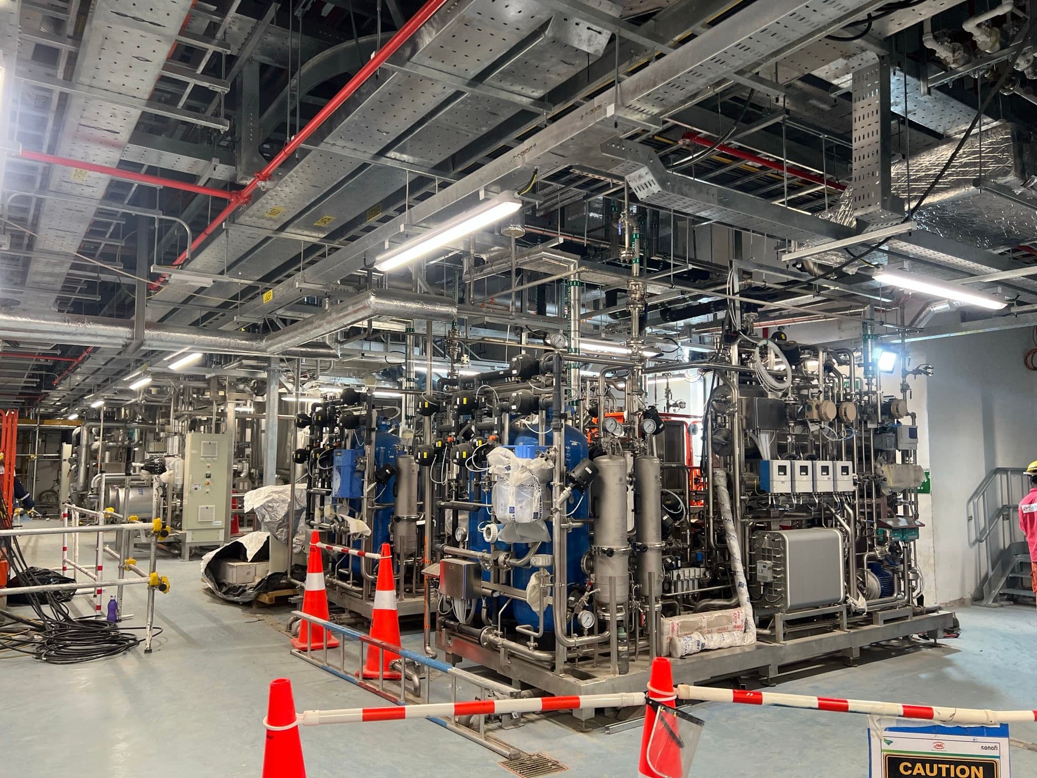 Stainless-steel water-generation skids and hygienic piping in a utility plantroom.